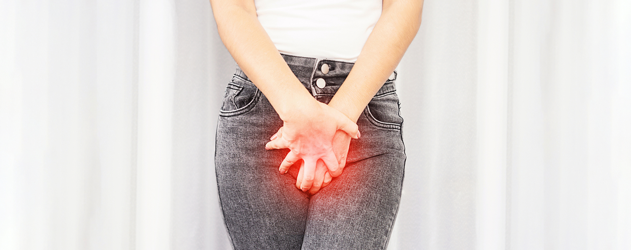 Kvinne som har vondt og holder seg for skrittet